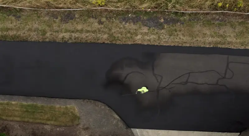 Professional crew with commercial equipment sealing a large driveway quickly and efficiently