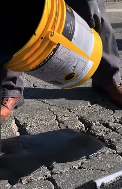 Un ouvrier d'une compagnie de scellant d'asphalte utilise un souffleur industriel pour nettoyer une entrée en asphalte avant l'application de scellant d'asphalte. Une préparation rigoureuse garantit que le scellant Gatineau adhère parfaitement.
