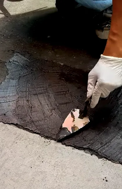 Application précise de scellant asphalte le long des bordures d'une entrée asphalte résidentielle. Ce travail minutieux de scellant signature protège le pavage contre l'effritement sur les rebords.